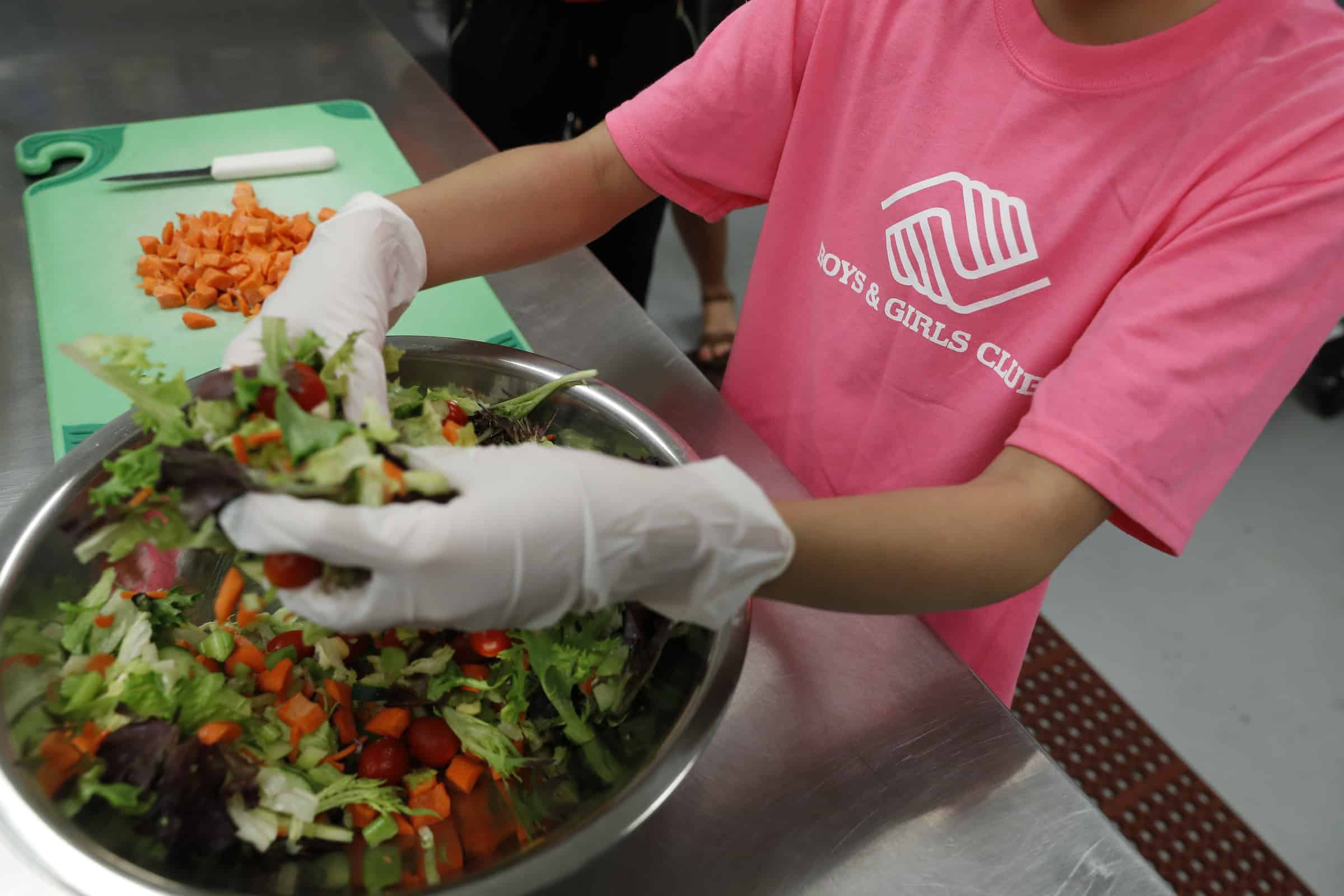 A volunteer making salad for the Boys & Girls Club food program